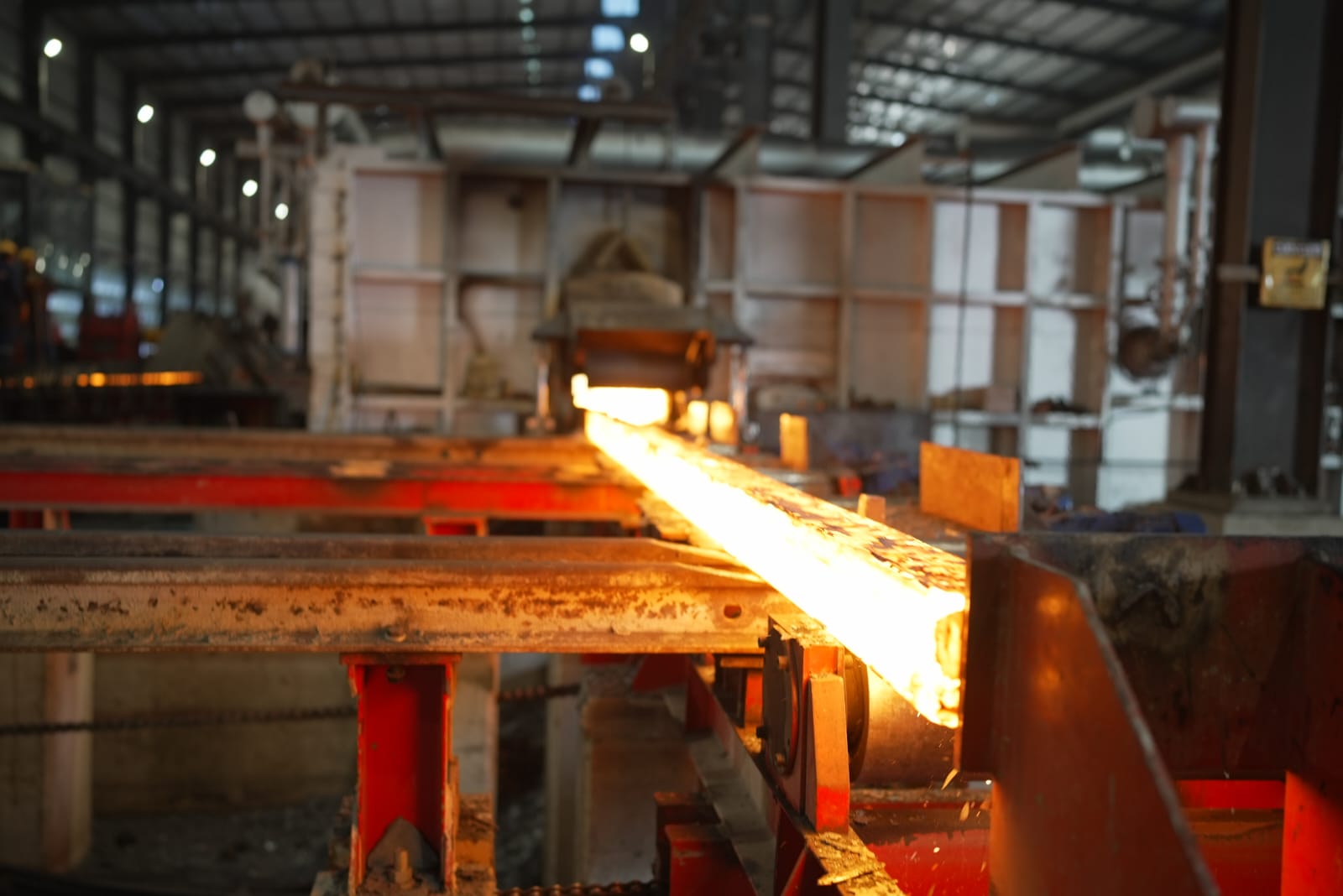Glowing steel billet moving through the rolling mill at Sabaeek Al-Hadeed