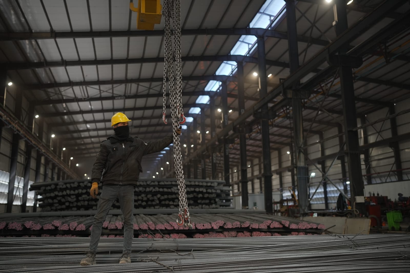 Worker walking past stacked rebar bundles in the storage yard